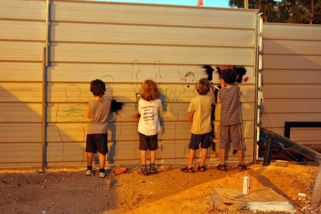 ילדי שכונת שפירא מציירים על הגדר של אתר הבנייה לדיור בר השגה שמיועד לאוכלוסיה חזקה שתגיע מבחוץ (צילום: שפי פז)